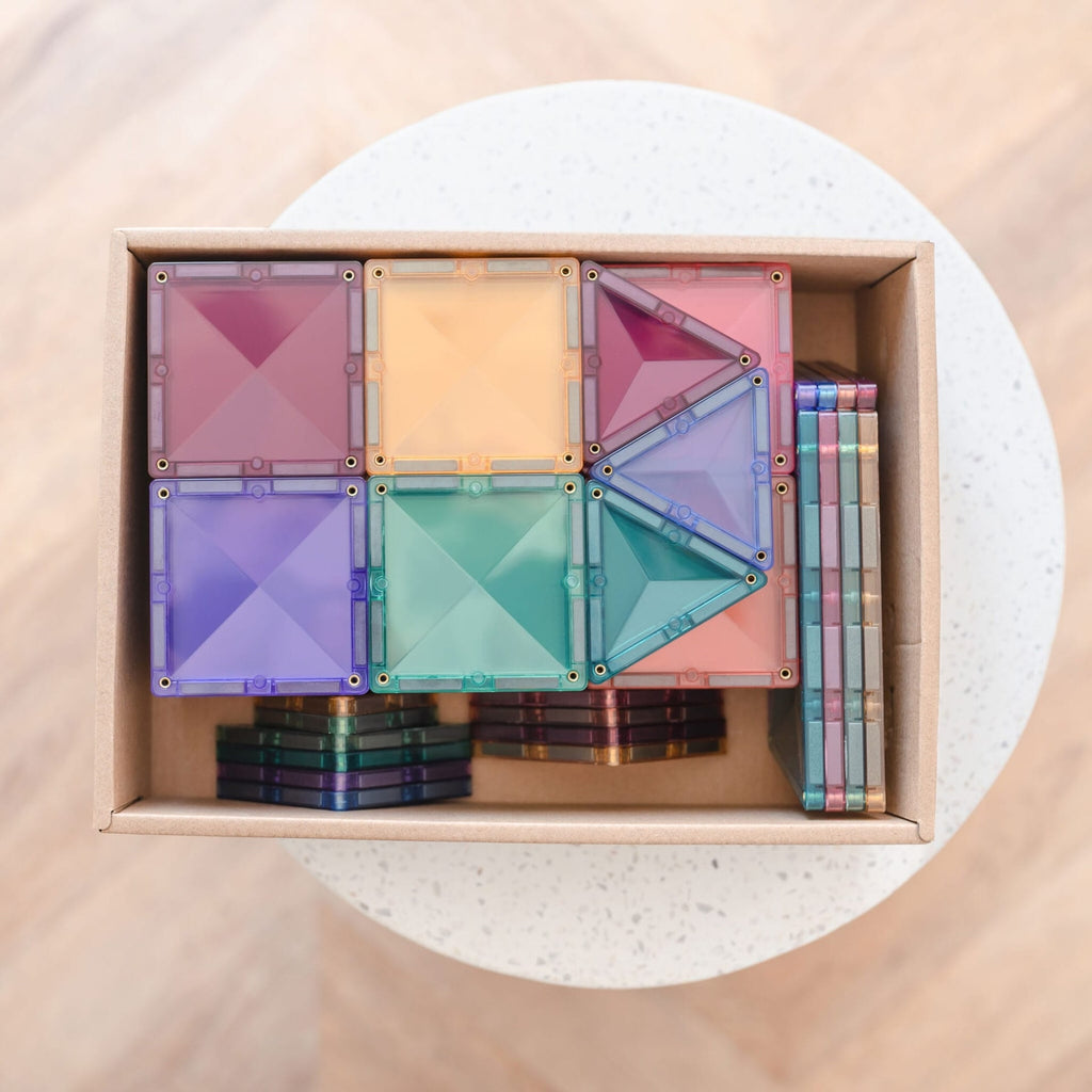 Colorful geometric magnetic building blocks in a wooden box on a light background