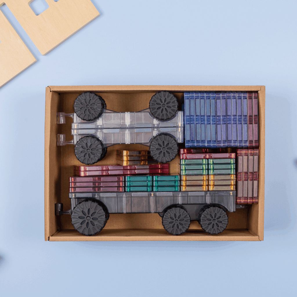 Wooden toy train set in a box with trees and a house on a light blue background