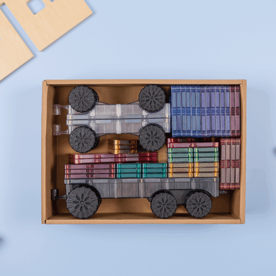 Wooden toy train set in a box with trees and a house on a light blue background