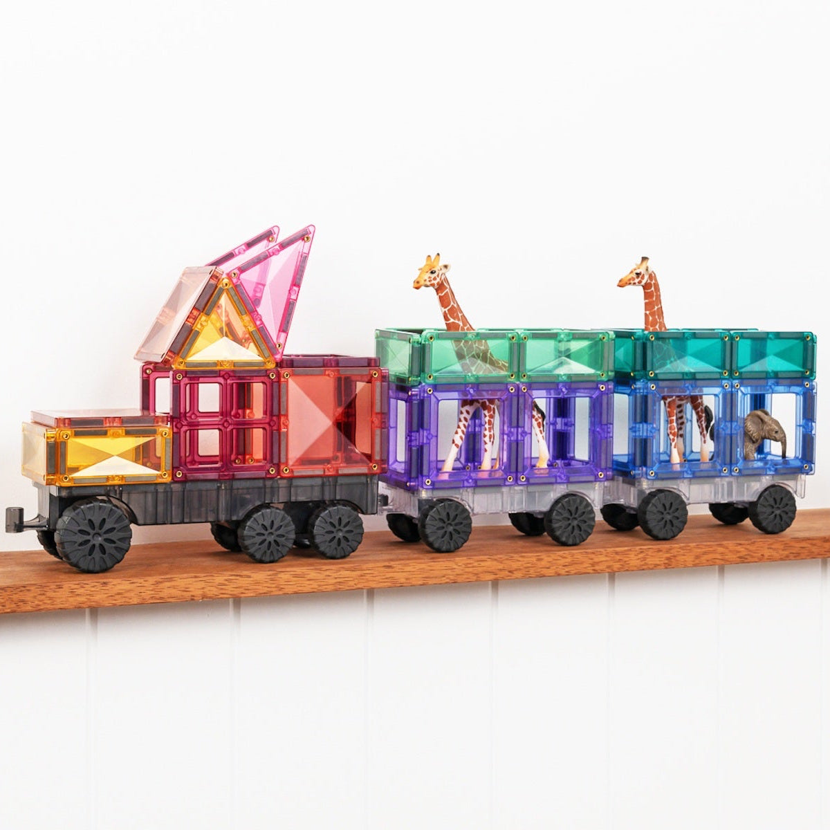 Colorful toy train with transparent cars on a wooden shelf against a white background