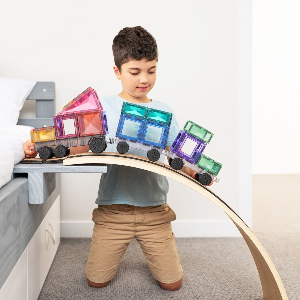 Child playing with a Connetix toy train on a bed