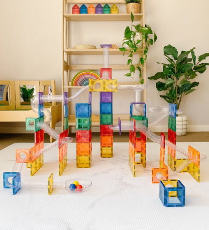 Colorful magnetic building blocks on a white surface with a shelf and plants in the background