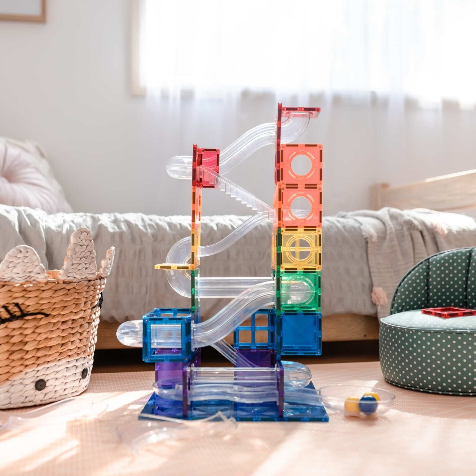 Colorful marble run toy set on a wooden floor with a cozy living room background.