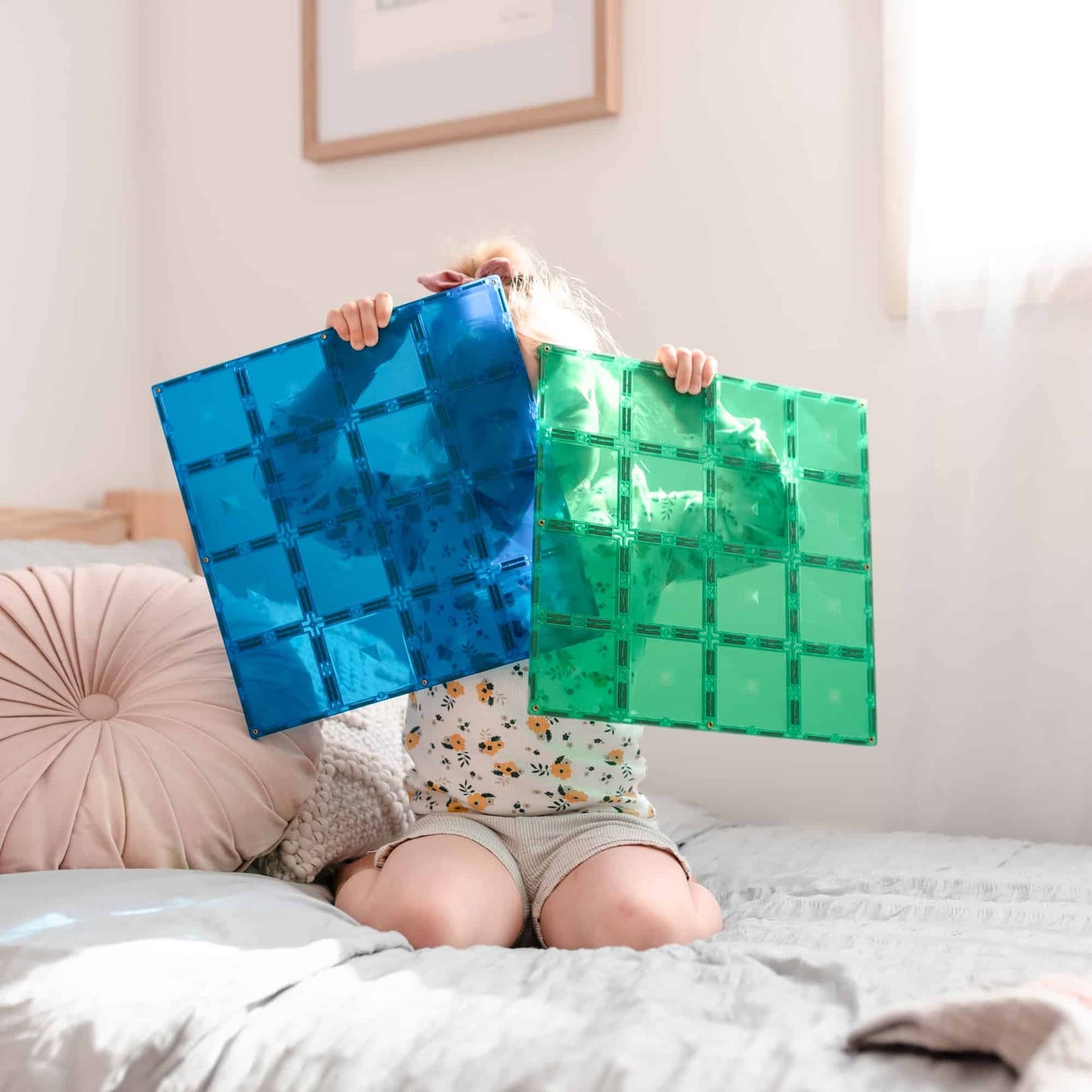 Person holding blue and green transparent tiles in a bedroom setting
