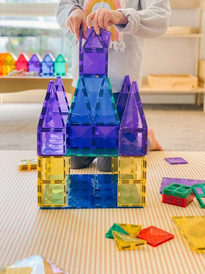 Child playing with colorful magnetic building blocks on a table.
