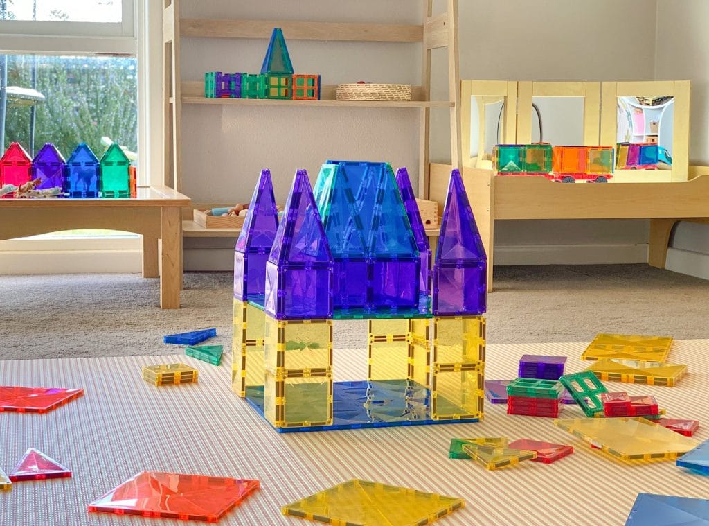 Colorful magnetic building blocks on a carpeted floor with shelves in the background
