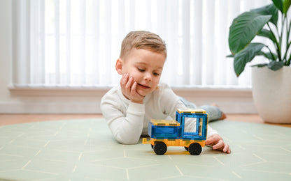Child playing with a toy truck on a tiled floor.