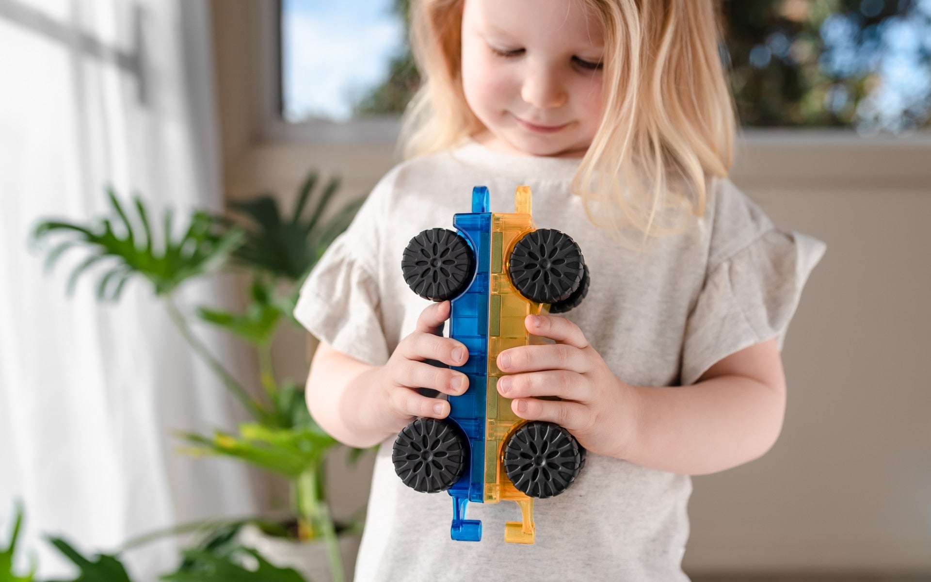 Child holding a toy with wheels indoors