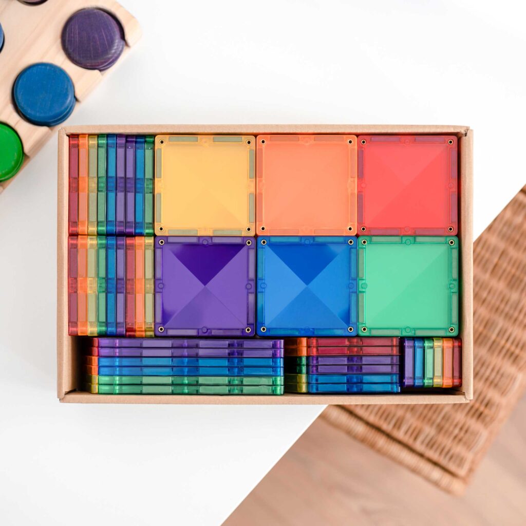 Colorful transparent square blocks in a wooden box on a light surface.