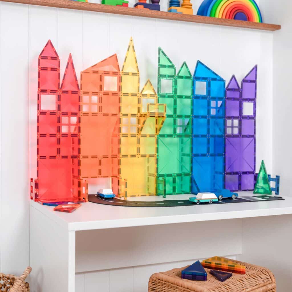 Colorful magnetic building toys on a white shelf with a rainbow-themed display above.