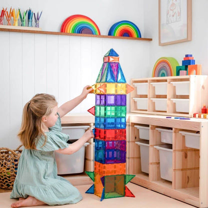 Child playing with colorful magnetic building blocks in a bright room.
