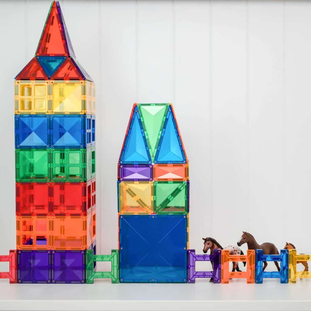 Colorful magnetic building towers with small horse figurines on a white background