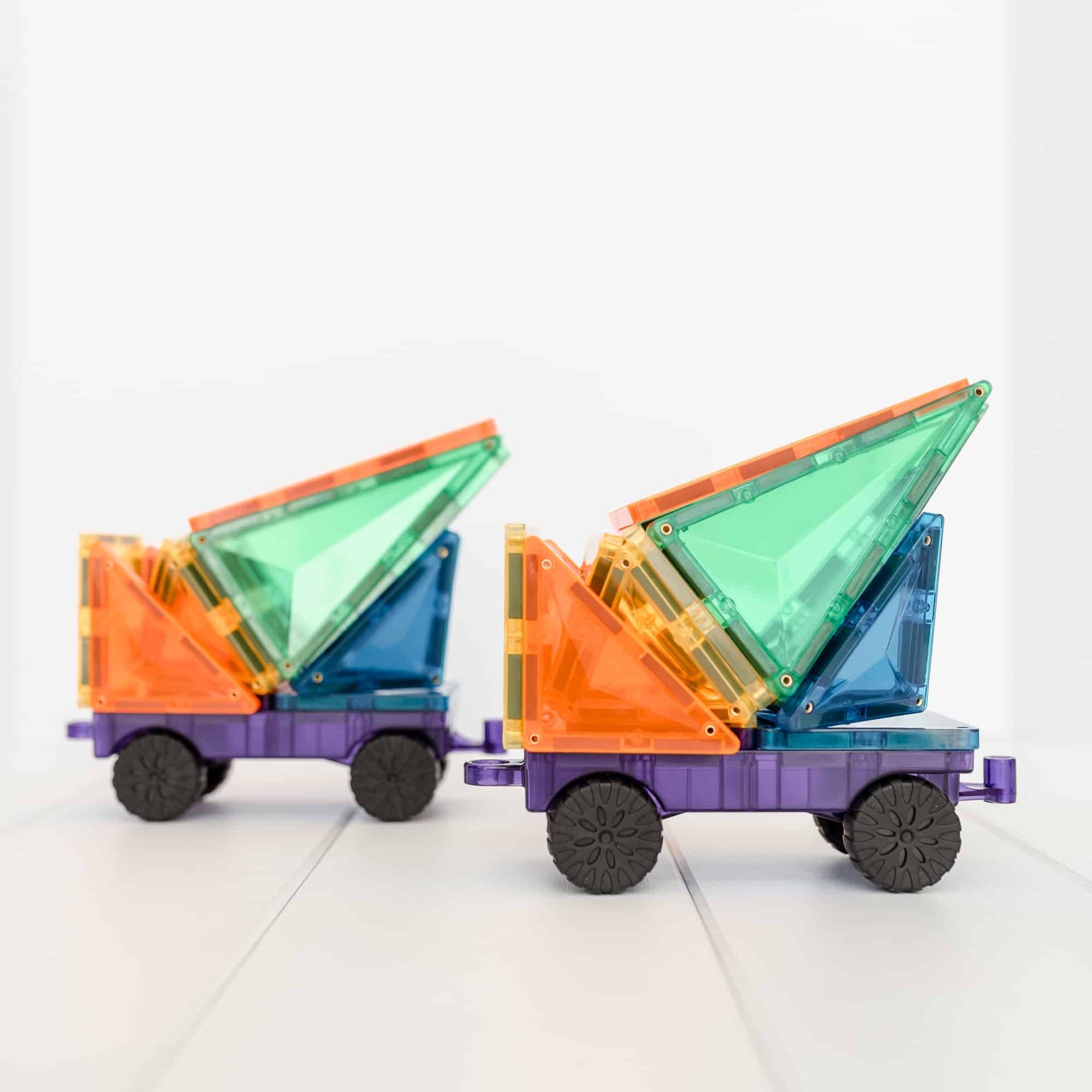 Colorful toy dump trucks made of interlocking plastic pieces on a white background