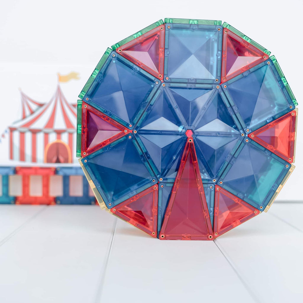 Colorful geometric toy structure on a white surface with a circus-themed backdrop