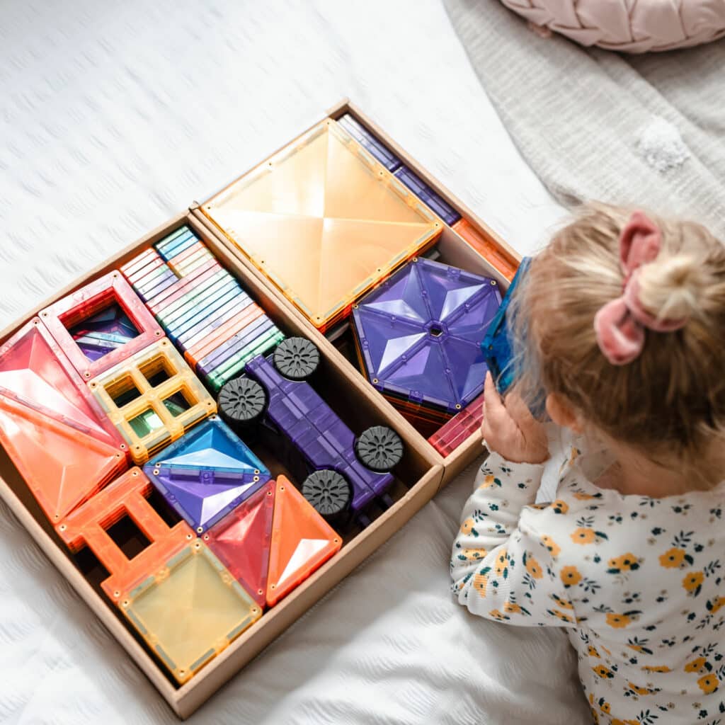 Child playing with colorful geometric building blocks on a bed