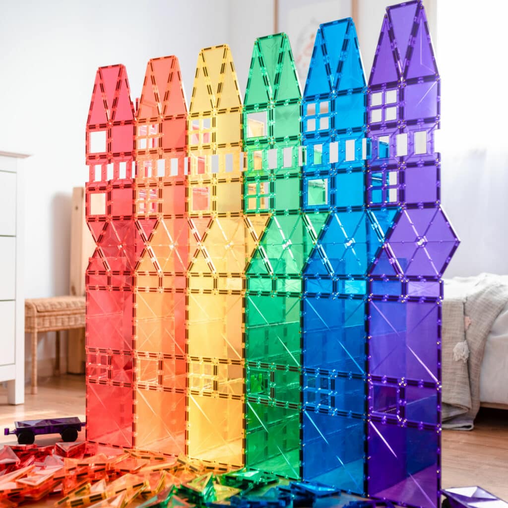Colorful magnetic building blocks stacked in a rainbow pattern on a wooden floor.