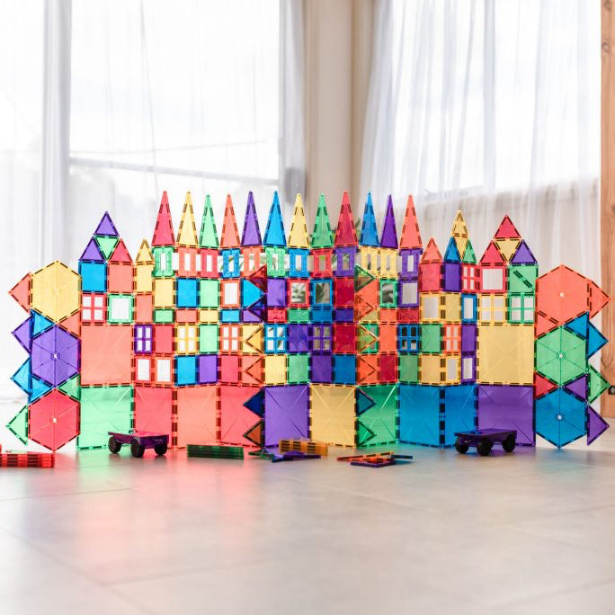 Colorful magnetic building blocks arranged to resemble a castle on a light wooden floor.