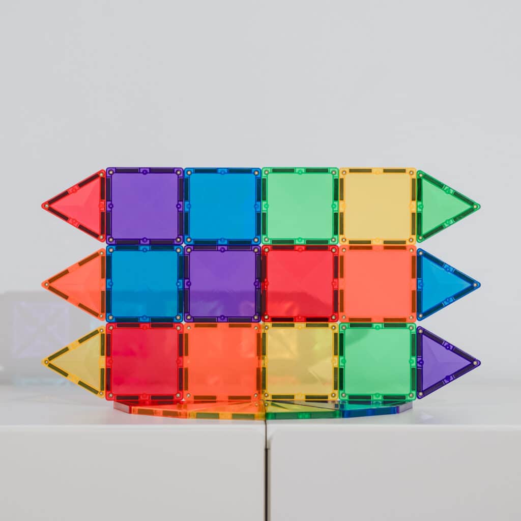 Colorful magnetic building blocks arranged in a rocket shape on a white background