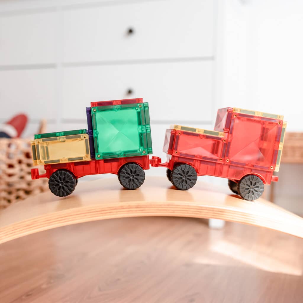 Colorful toy train cars on a wooden track with a white background