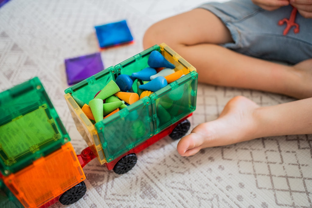 Colorful toy truck with building blocks on a textured surface, child's legs visible.