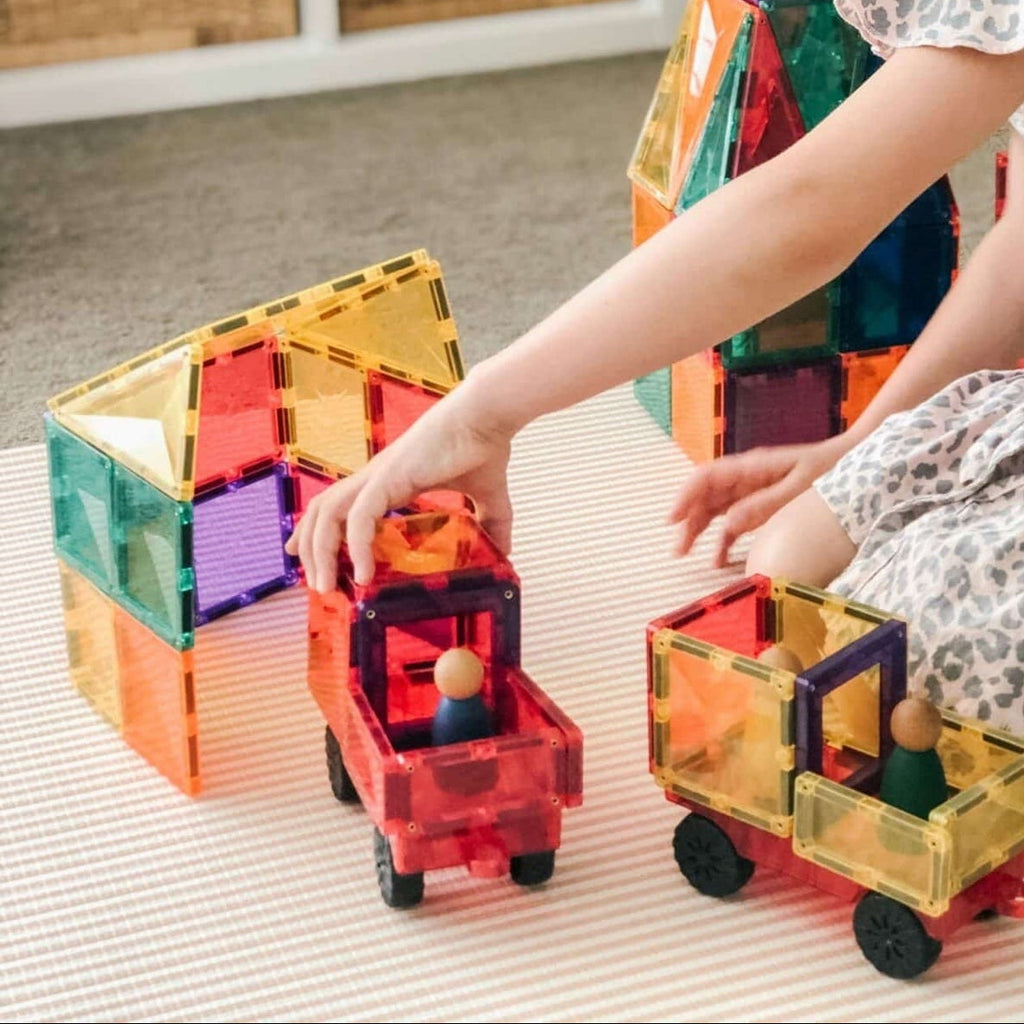 Child playing with colorful magnetic building blocks on a light surface.
