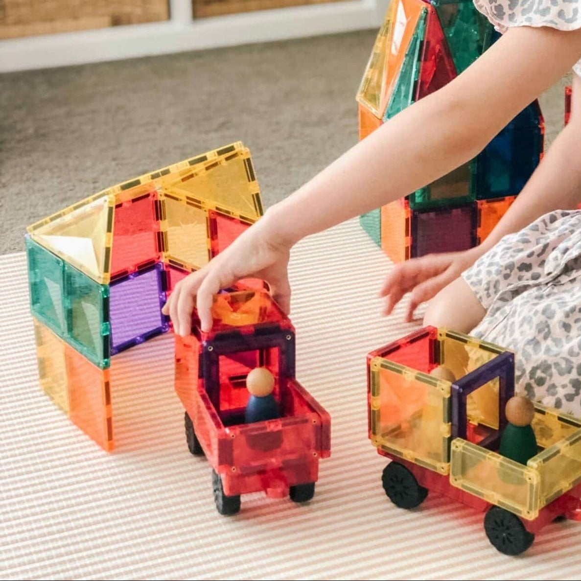 Child playing with colorful magnetic building blocks on a light surface.