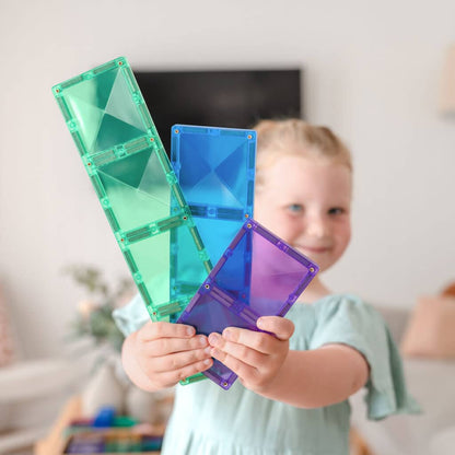 Child holding colorful transparent geometric shapes in a home setting