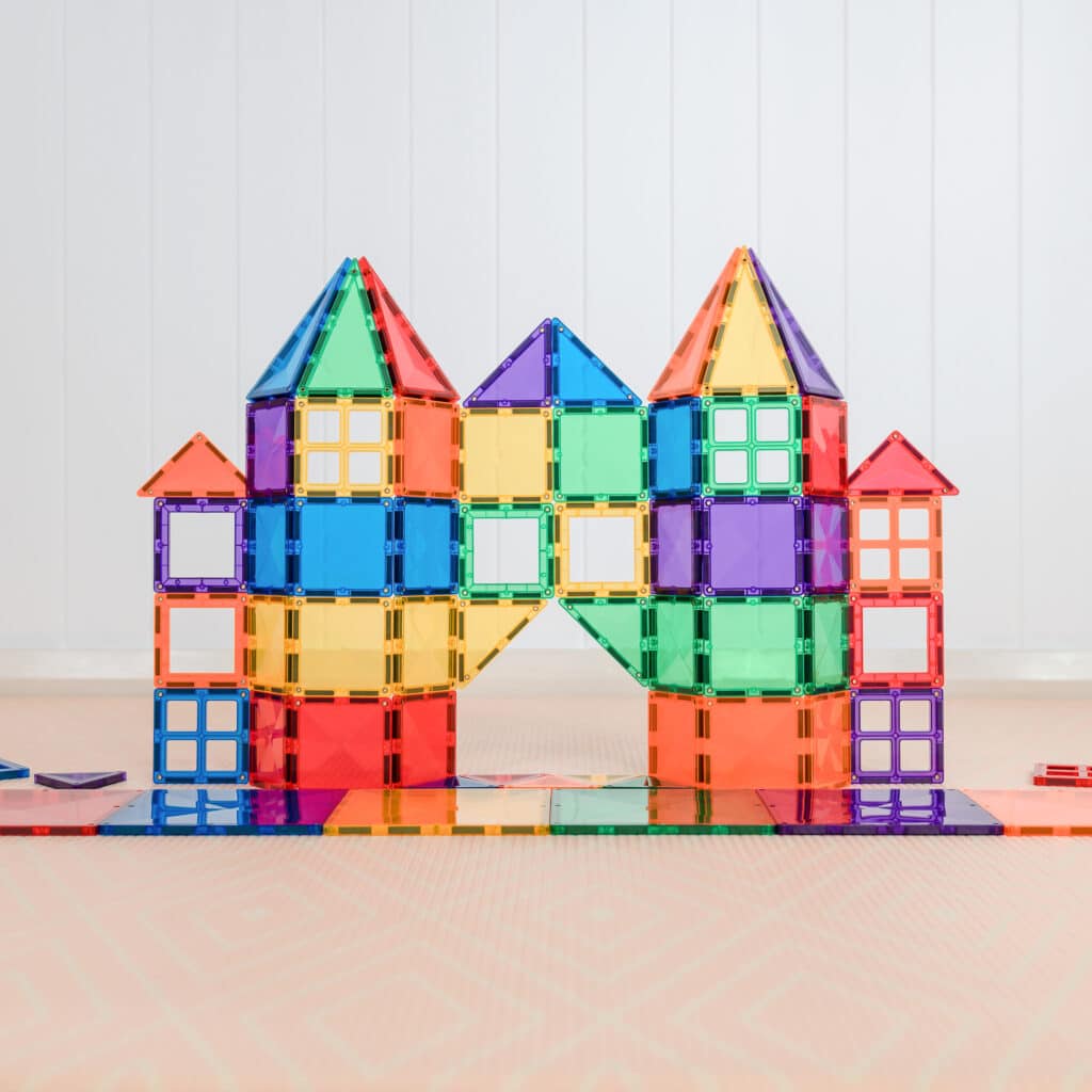 Colorful magnetic building block castle on a reflective surface with a light wooden background
