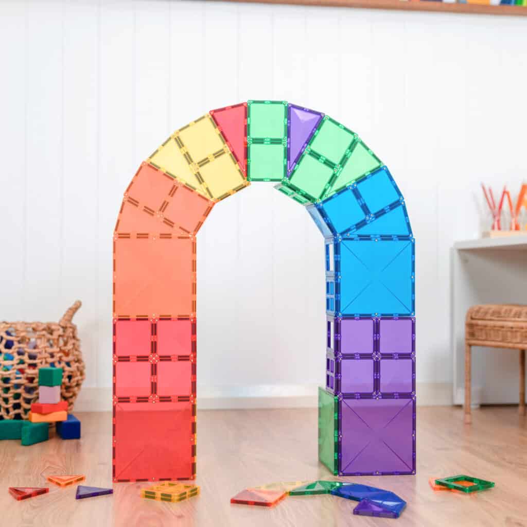 Colorful arch made of interlocking toy bricks on a wooden floor.