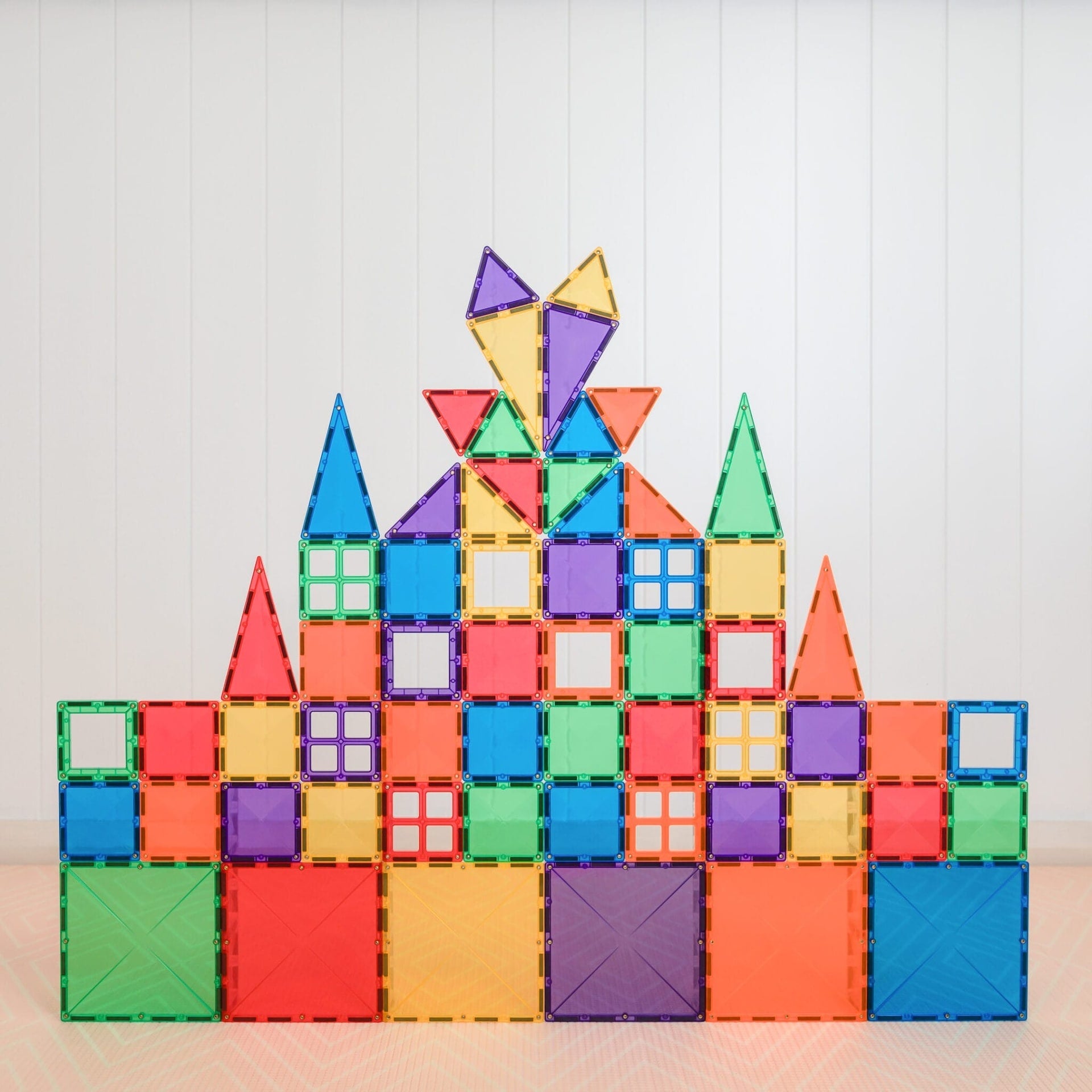 Colorful magnetic building blocks arranged to form a castle on a light background