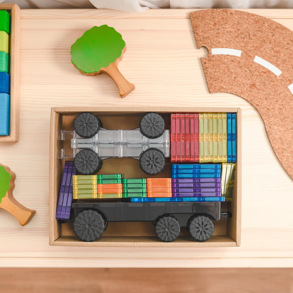Colorful toy truck made of interlocking blocks on a wooden surface with a cork board in the background.