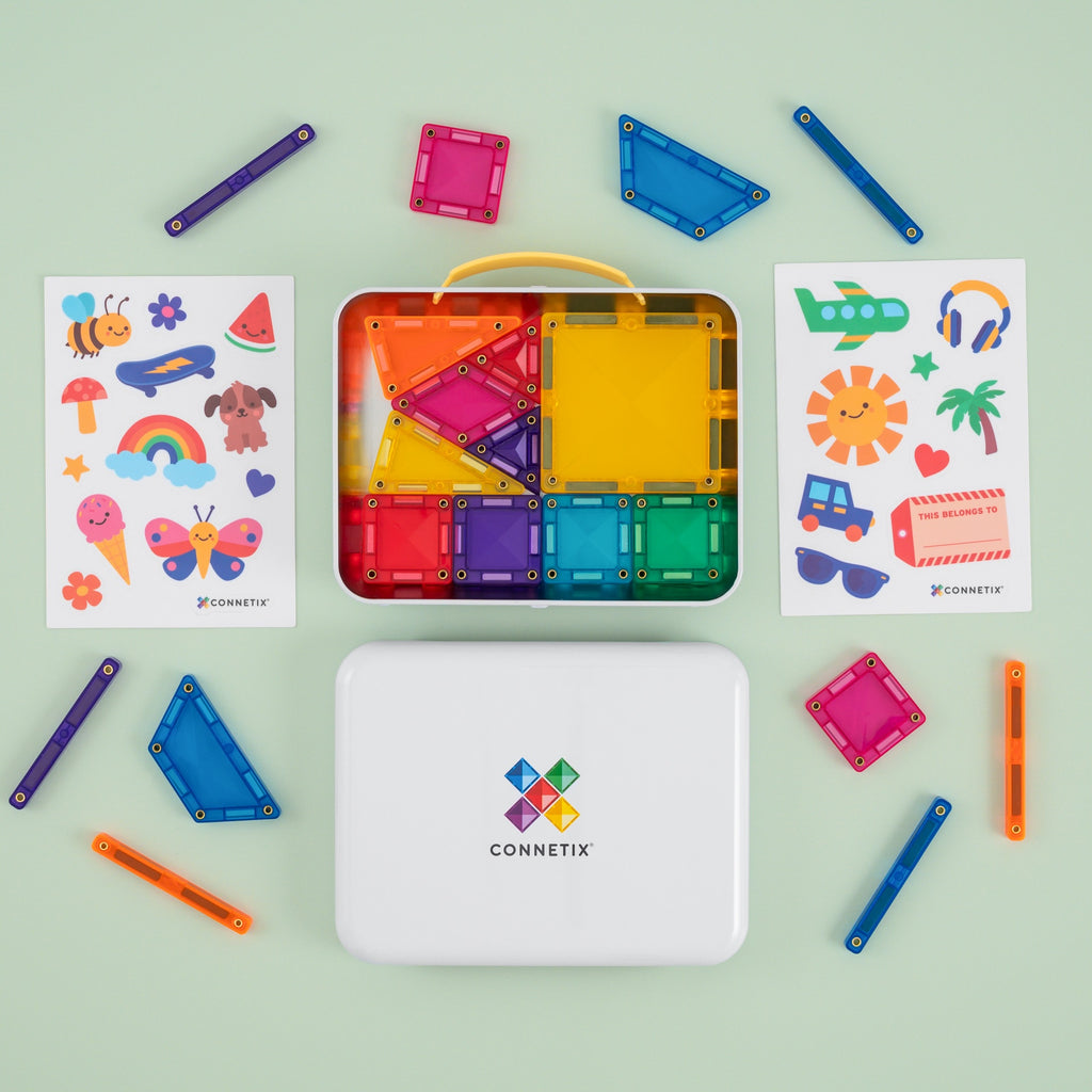 Connetix magnetic tile building set arranged on a pale green background, including a white storage case, an open tray of colorful magnetic tiles, two printed sticker sheets, and several loose tiles and sticks.