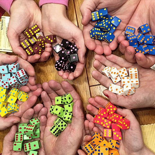 Hands holding colorful dice on a wooden surface