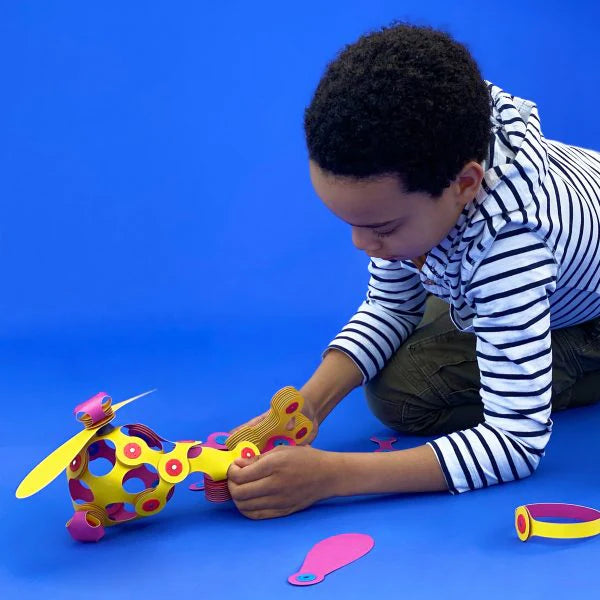 Child playing with a colorful paper helicopter on a blue background