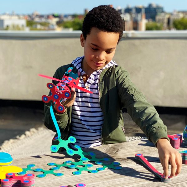 Child playing with colorful toys on a rooftop with cityscape in the background