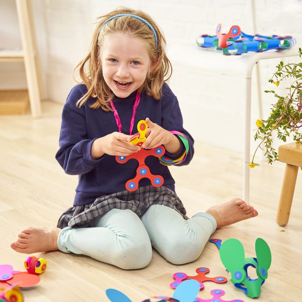 Child playing with colorful Clixo on a wooden floor.
