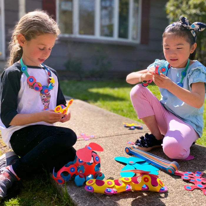Two children playing with colorful toys on a concrete surface outdoors.