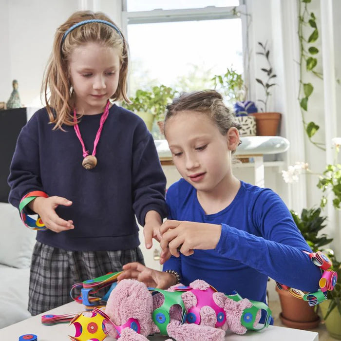 Two children playing with colorful toys on a table in a bright room.