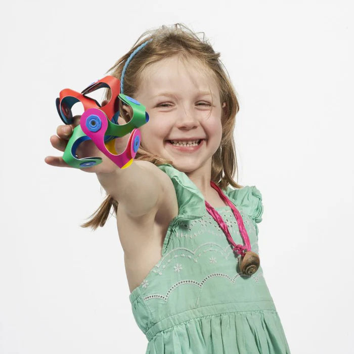 Young girl holding a colorful toy with a plain background