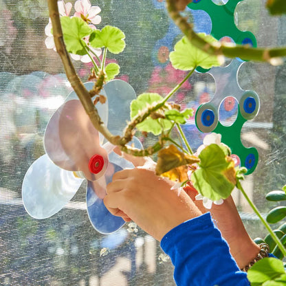 Child's hand holding Clixo, against a blurred outdoor background