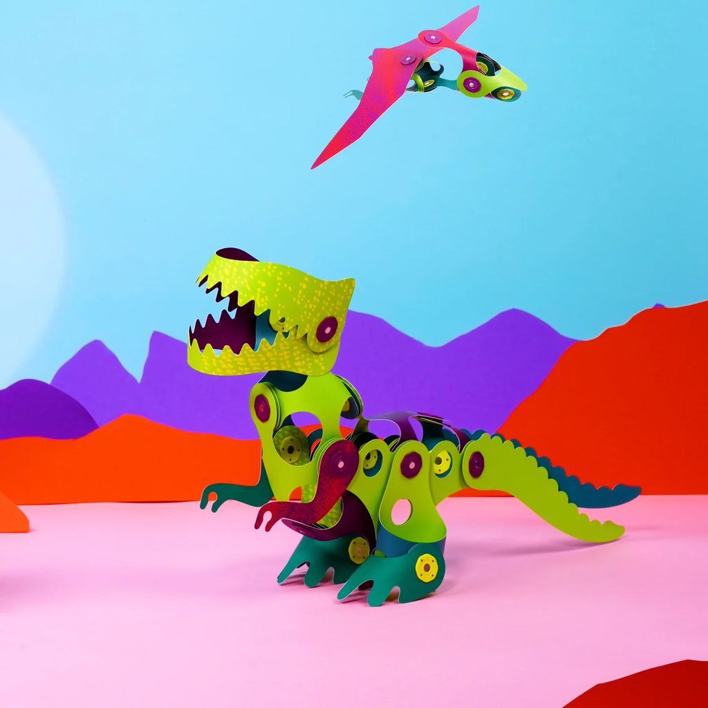 Colorful dinosaur toys on a pink surface with a blue sky and purple mountains in the background.