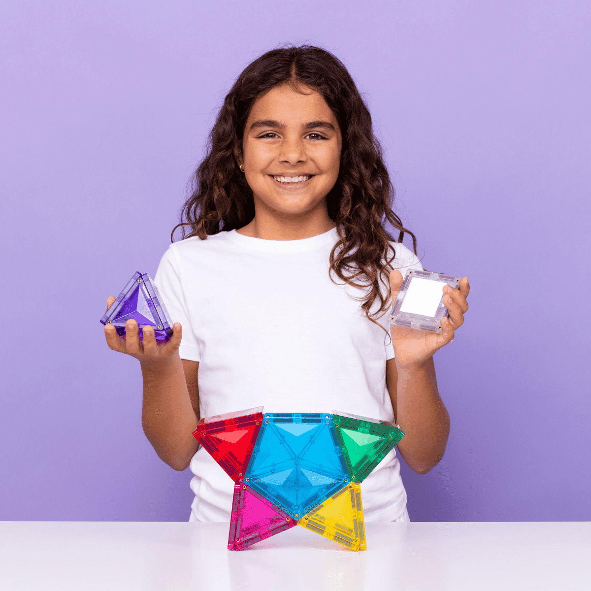 Girl holding colorful geometric shapes against a purple background