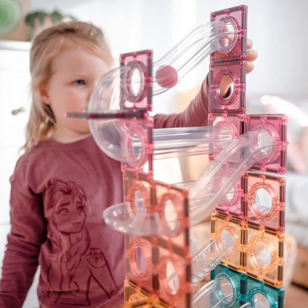 Child playing with a transparent and pink ball run