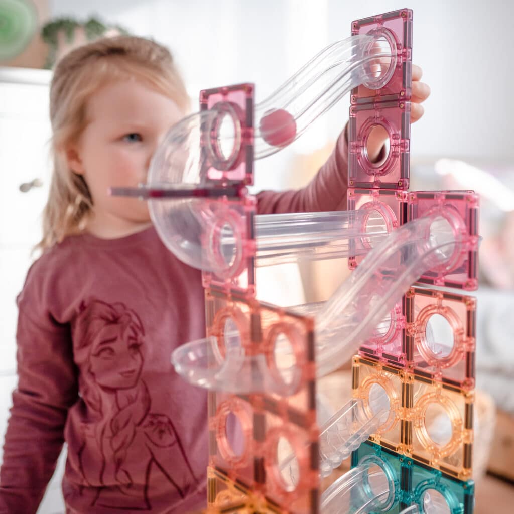 Child playing with a transparent and pink ball run