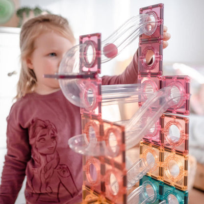 Child playing with a transparent and pink ball run