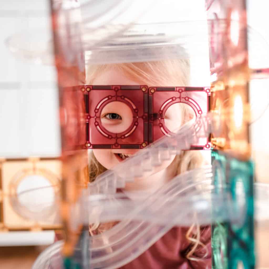 Child looking through magnetic tile ball run.