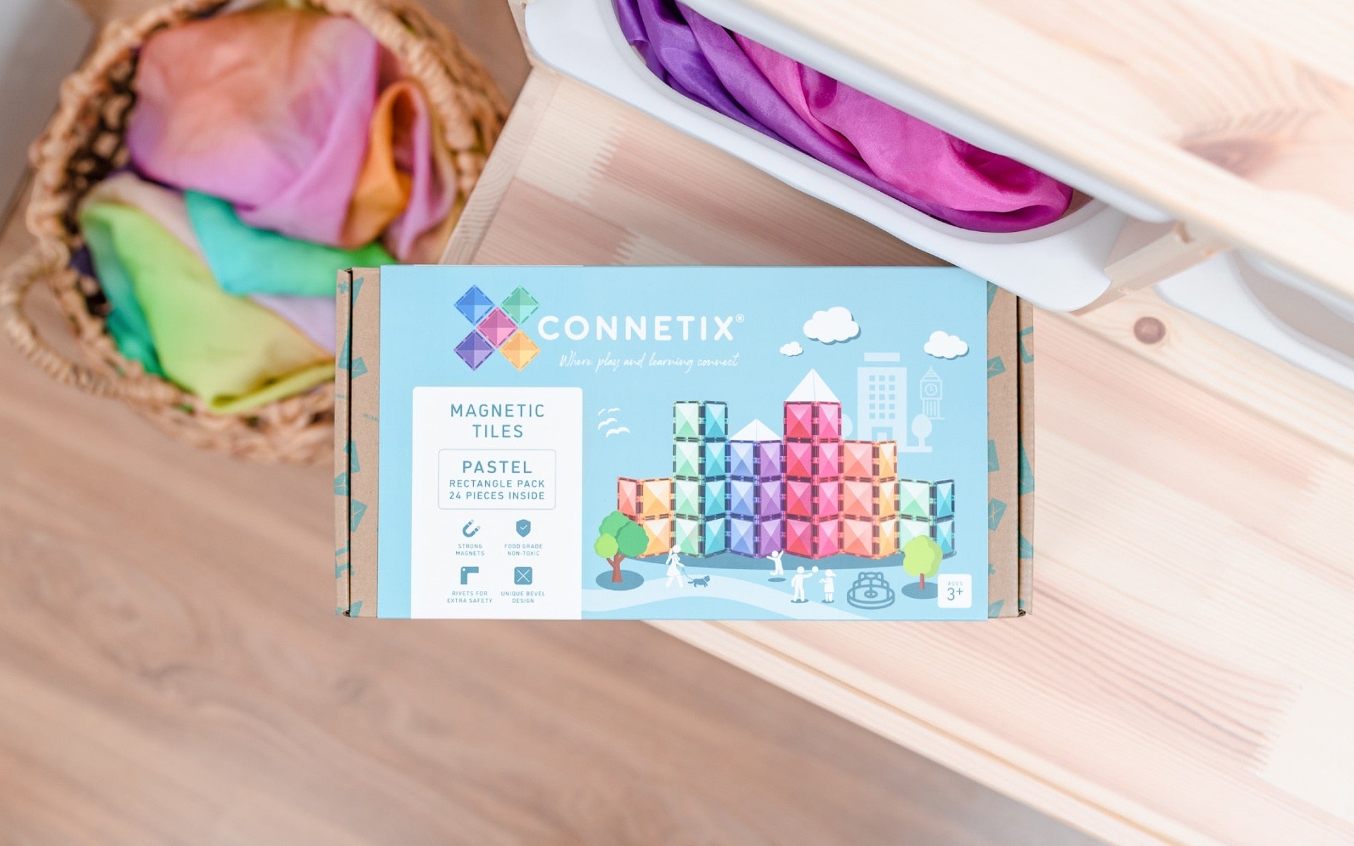 Connetix magnetic tiles packaging on a wooden surface with colorful tiles in the background