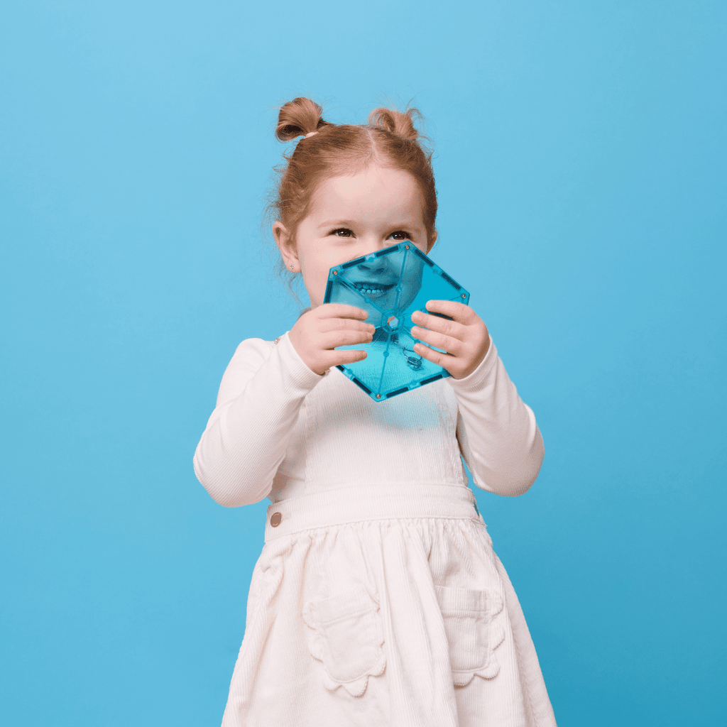 Child holding a blue tile against a blue background