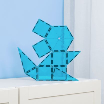 Blue geometric sculpture on a white surface with a light blue wall background