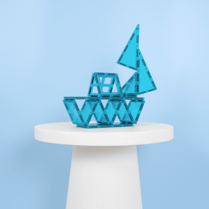 Blue geometric sculpture on a white pedestal against a light blue background